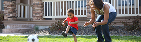 Family Playing Soccer Mom and son playing with a soccer ball outside their house